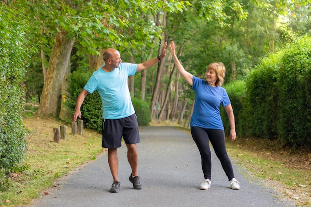 Man and woman giving five to each other after having finished an exercise well in an urban park