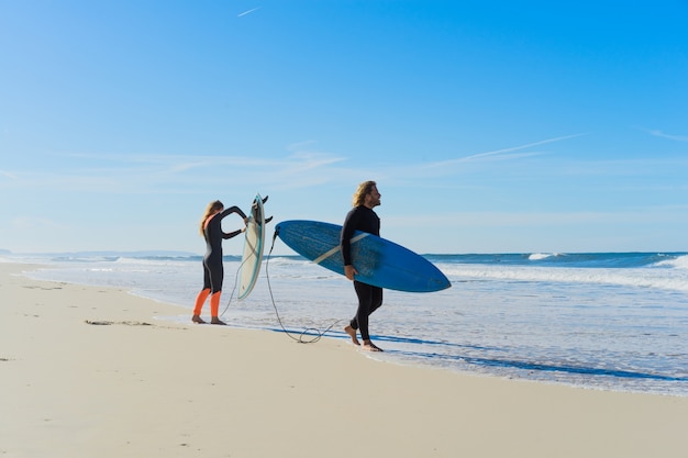 man and woman go to the ocean with surf boards. man and girl go surfing