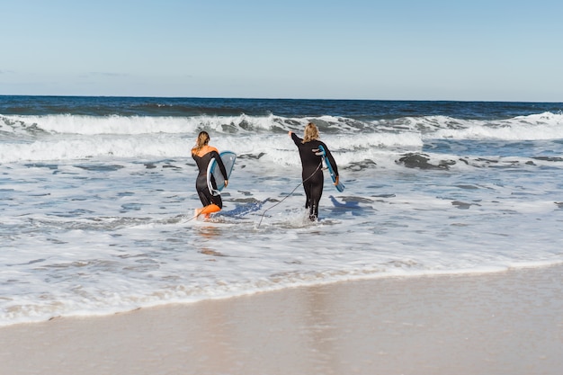 man and woman go to the ocean with surf boards. man and girl go surfing