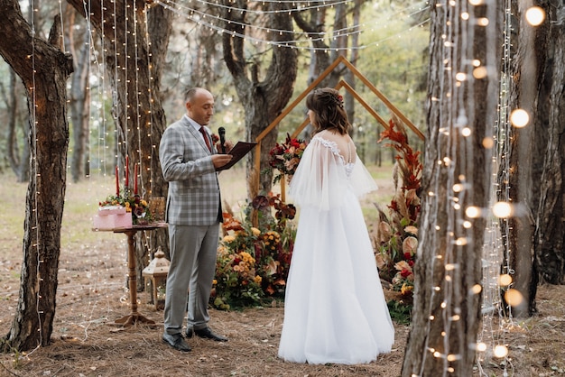 Man and woman got engaged in autumn forest at wedding decorated ceremony