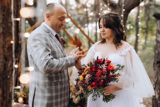 Man and woman got engaged in autumn forest at wedding decorated ceremony