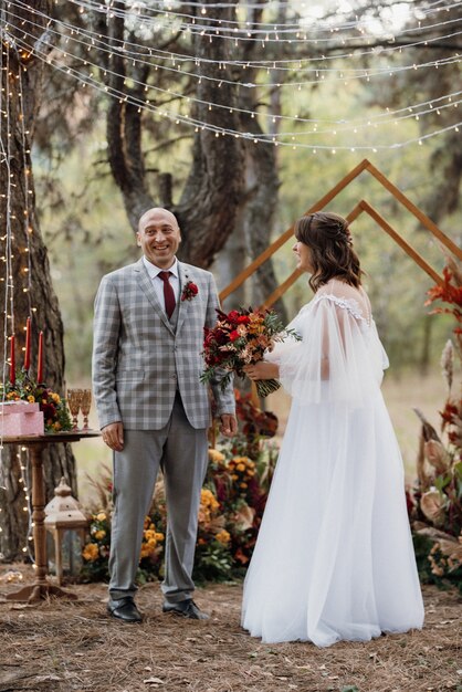 Man and woman got engaged in autumn forest at wedding decorated ceremony