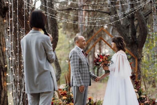 Man and woman got engaged in autumn forest at wedding decorated ceremony