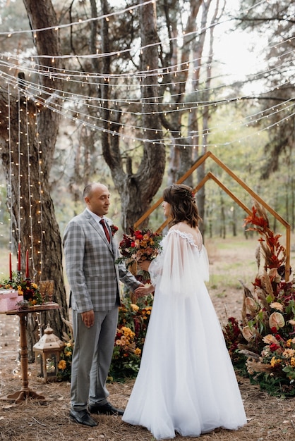 Man and woman got engaged in autumn forest at wedding decorated ceremony