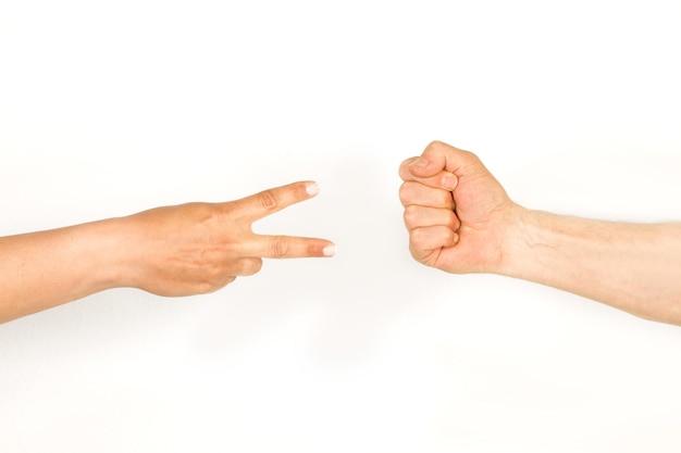 Man and woman hands doing rock paper scissors game on a white\
background with copy space