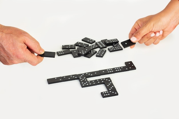 Man and woman hands holding domino pieces on a white background with copy space