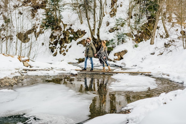 Man and woman happy couple hikers trekking in green winter forest and mountains Young people walking...