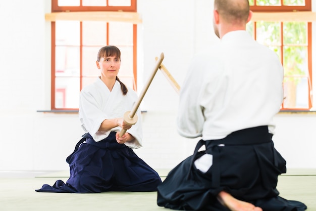 Photo man and woman having aikido sword fight