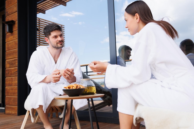 Photo man and woman having tea sitting on the terrace in bathrobes