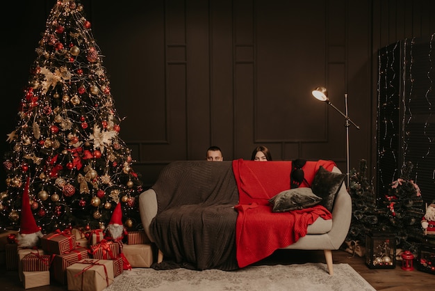 Man and a woman hid behind couch. heads of a man and a woman stick out from behind sofa.