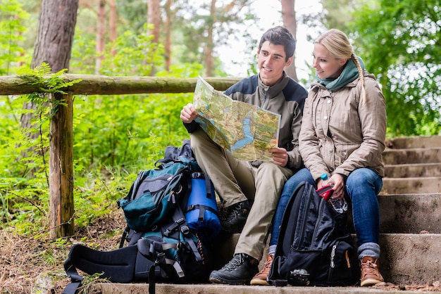 Man and woman on hike in forest planning next route section on map