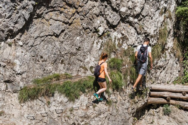 Foto uomo e donna che camminano sul sentiero ripido sopra il fiume di montagna