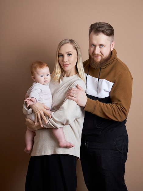 Photo man and a woman hold a baby in their arms. portrait of a married couple after the birth of a child. young family