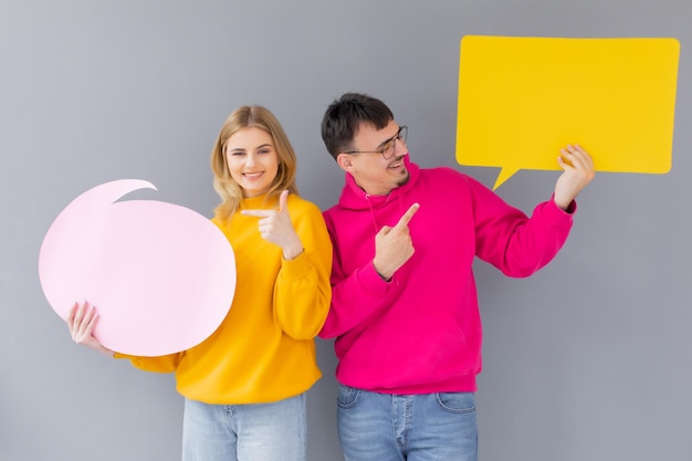 The man and woman hold a dialog signs on the grey background