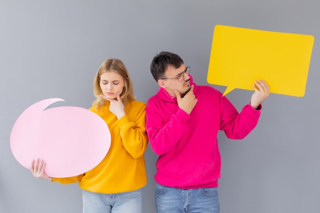 The man and woman hold a dialog signs on the grey background