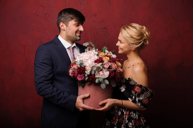 Man and woman holding the bouquet of flowers looking into eyes