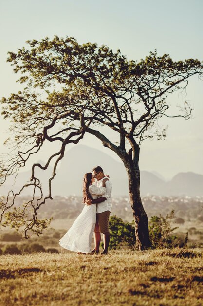Man and woman in holding each other standing beside tree photo