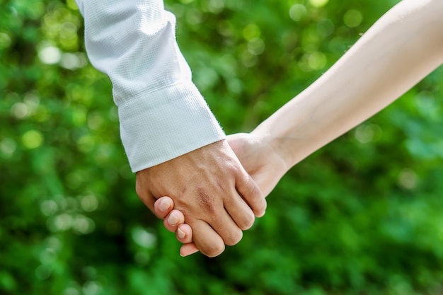 Uomo e donna che si tengono per mano su una natura verde