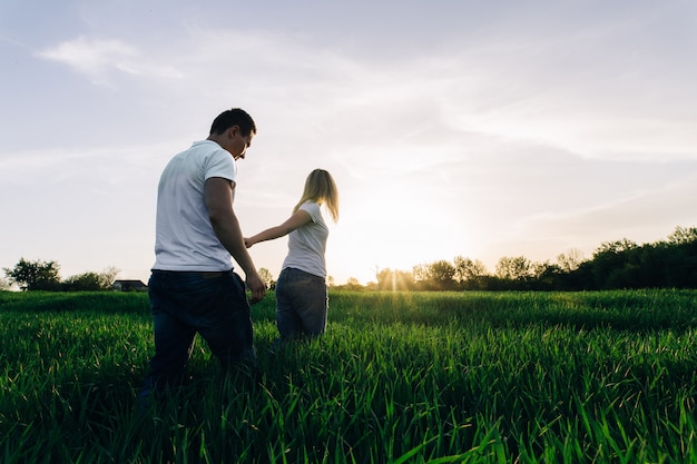 男と女の屋外の愛の物語の緑の春のgrass.conceptに手をつないで