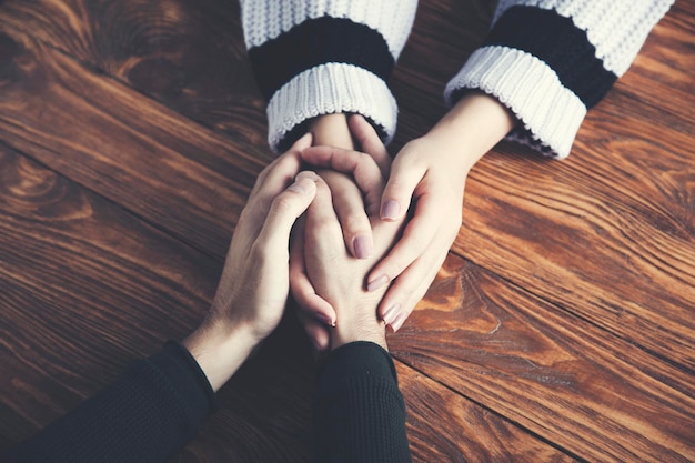 Man and a woman holding hands at a wooden table