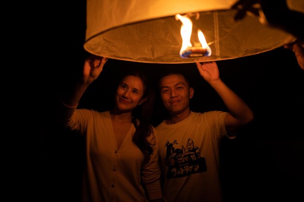 Мужчина и женщина, держащие бумажный фонарь во время фестиваля Yi Peng в Чианг-Май, Таиланд