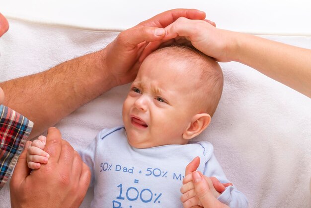 Man and woman holding son crying on bed at home