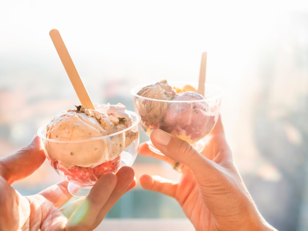 Foto uomo e donna tengono ciotole di plastica con gelato freddo dessert gelato con cucchiai data romantica