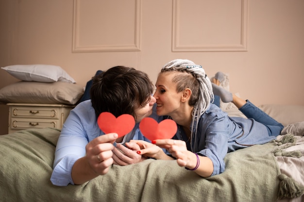 Man and woman at home kissing with red heart valentine in hands.  