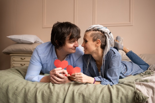   Man and woman at home looking at each other with red heart valentine in hands.