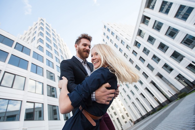 Photo man and woman hugging and laughing in front of a white building. bottom view