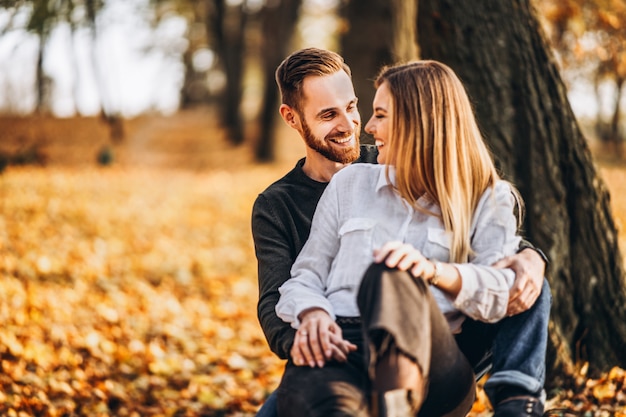 Uomo e donna che abbracciano e che sorridono nel parco autunnale