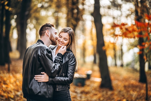 Man and woman hugging and smiling in the background of autumn park.