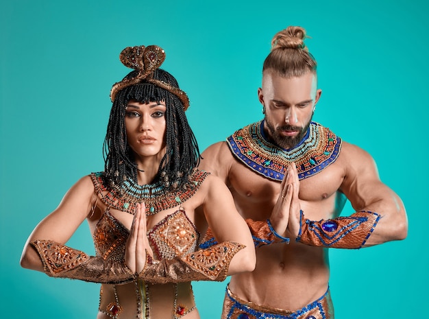 Photo the man and woman in the images of egyptian pharaoh and cleopatra on blue studio background