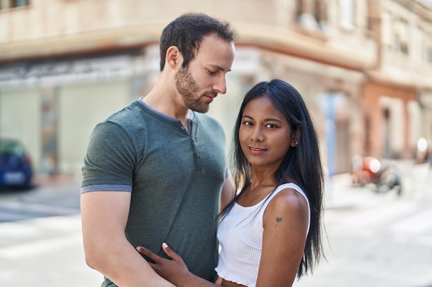 Man and woman interracial couple hugging each other at street