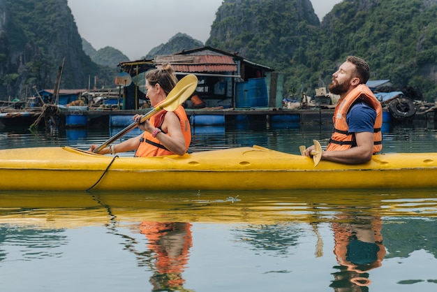 Man and woman in kayak relaxing on the sun during trip in Ha Long Bay, Vietnam