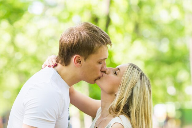 Мужчина и женщина целуются в парке летом