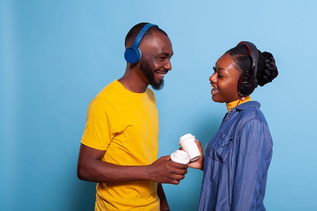 Man and woman laughing and listening to song on headset in studio. Playful couple enjoying playlist music on headphones, feeling happy together. Girlfriend and boyfriend having fun with audio