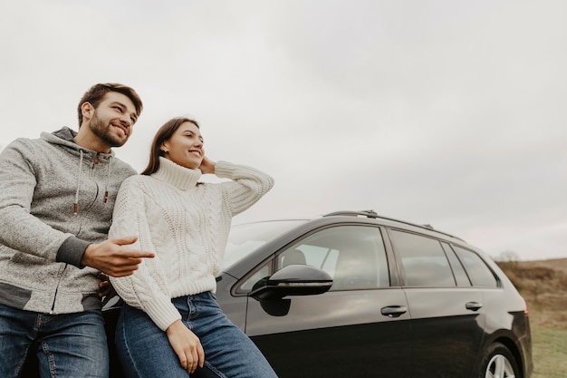 Man and woman leaning on car