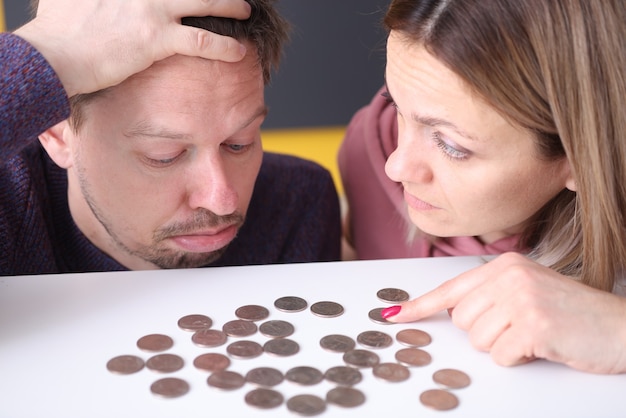 Man and a woman look upset at coins on table. family budget planning concept