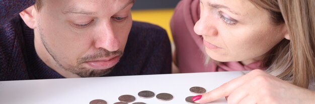 Foto un uomo e una donna sembrano sconvolti dalle monete sul concetto di pianificazione del bilancio familiare del tavolo table