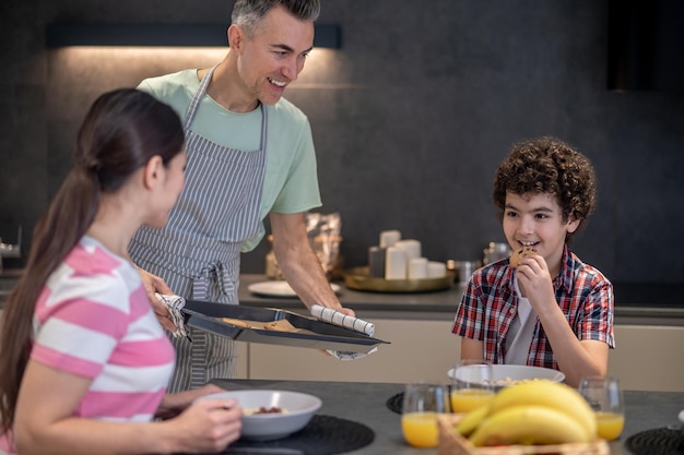 Man and woman looking at boy trying cookies