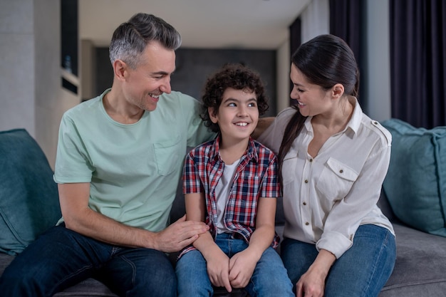 Man and woman looking at son sitting on sofa