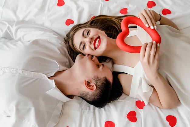 Man and woman in love in bed with heart shaped confetti