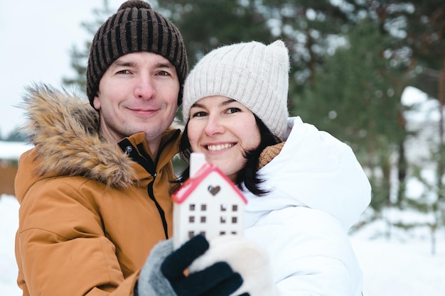 Man and woman in love outdoor date in winter with symbol of home and love. Valentine's Day, happy couple, love story. Love nest, mortgage, relocation, purchase, real estate, housing for young family