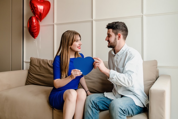 Man and woman in love with red heart shaped valentine card and balloons