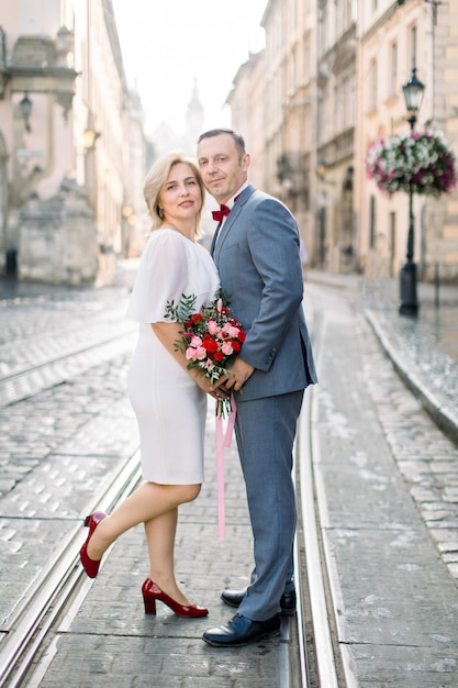 Man and woman in luxury clothes, posing together on tram railroad in ancient old city center