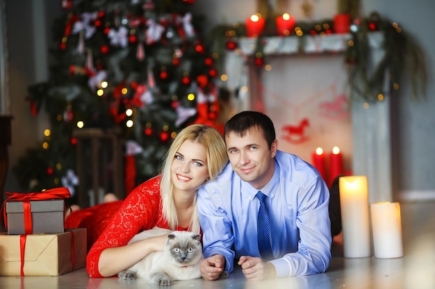 A man and a woman a married couple lie on their stomach near the fireplace and next to them Christmas gifts