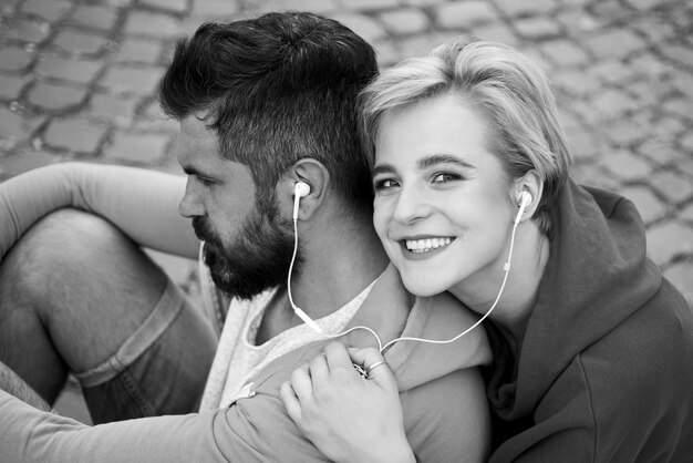 Man and woman in modern clothes listen music outdoor