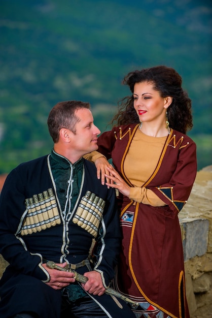 A man and a woman in the national dress of Georgia against the backdrop of the mountains.