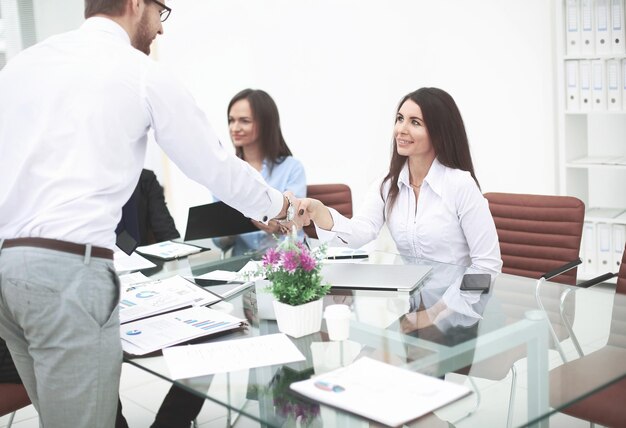 Man and woman partners shaking hands over the table maintaining eye contact